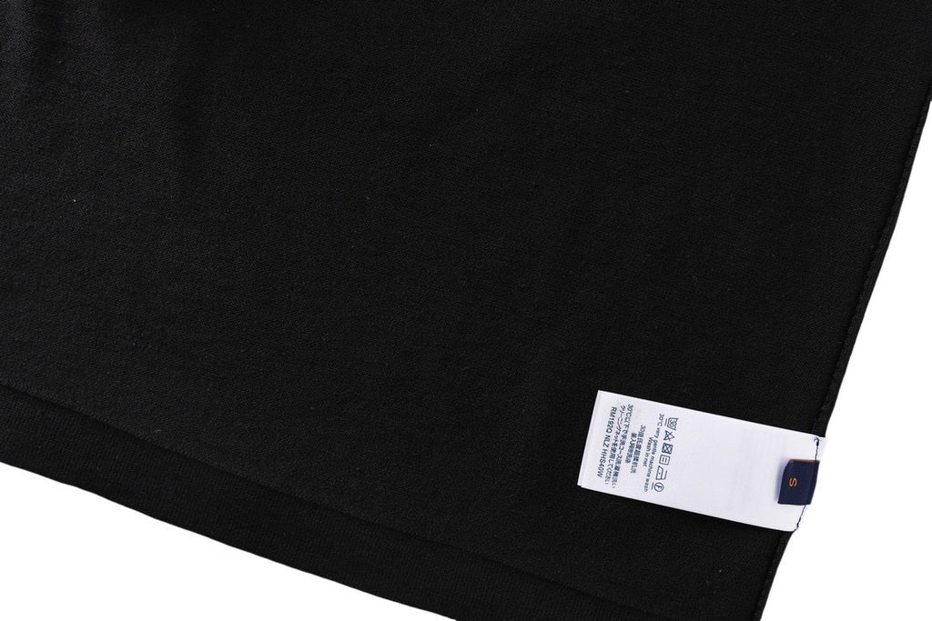 Black T-shirt folded hem with white size label and blue dot