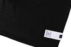 Black T-shirt folded hem with white size label and blue dot