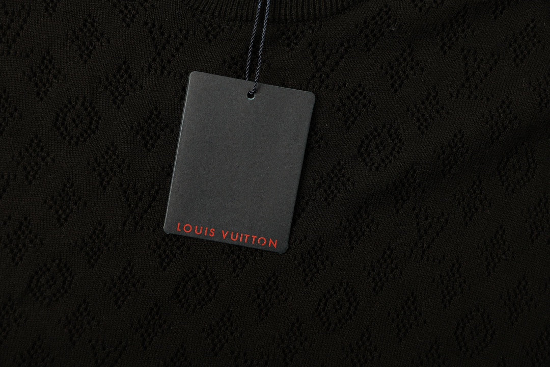 Black T-shirt fabric with subtle monogram pattern and hanging logo tag