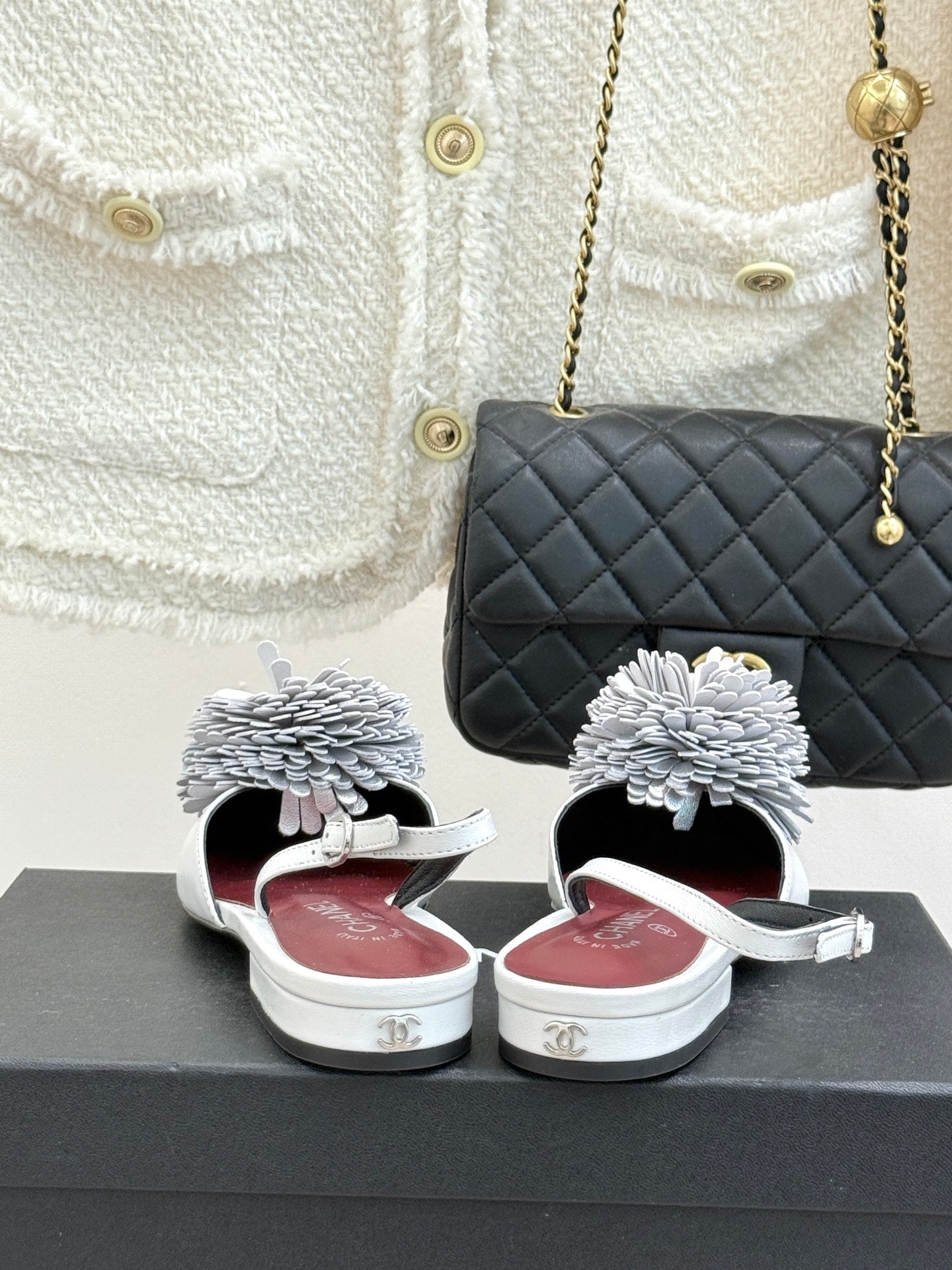 Chanel slingback flats with white flower appliqués, white straps, on a box