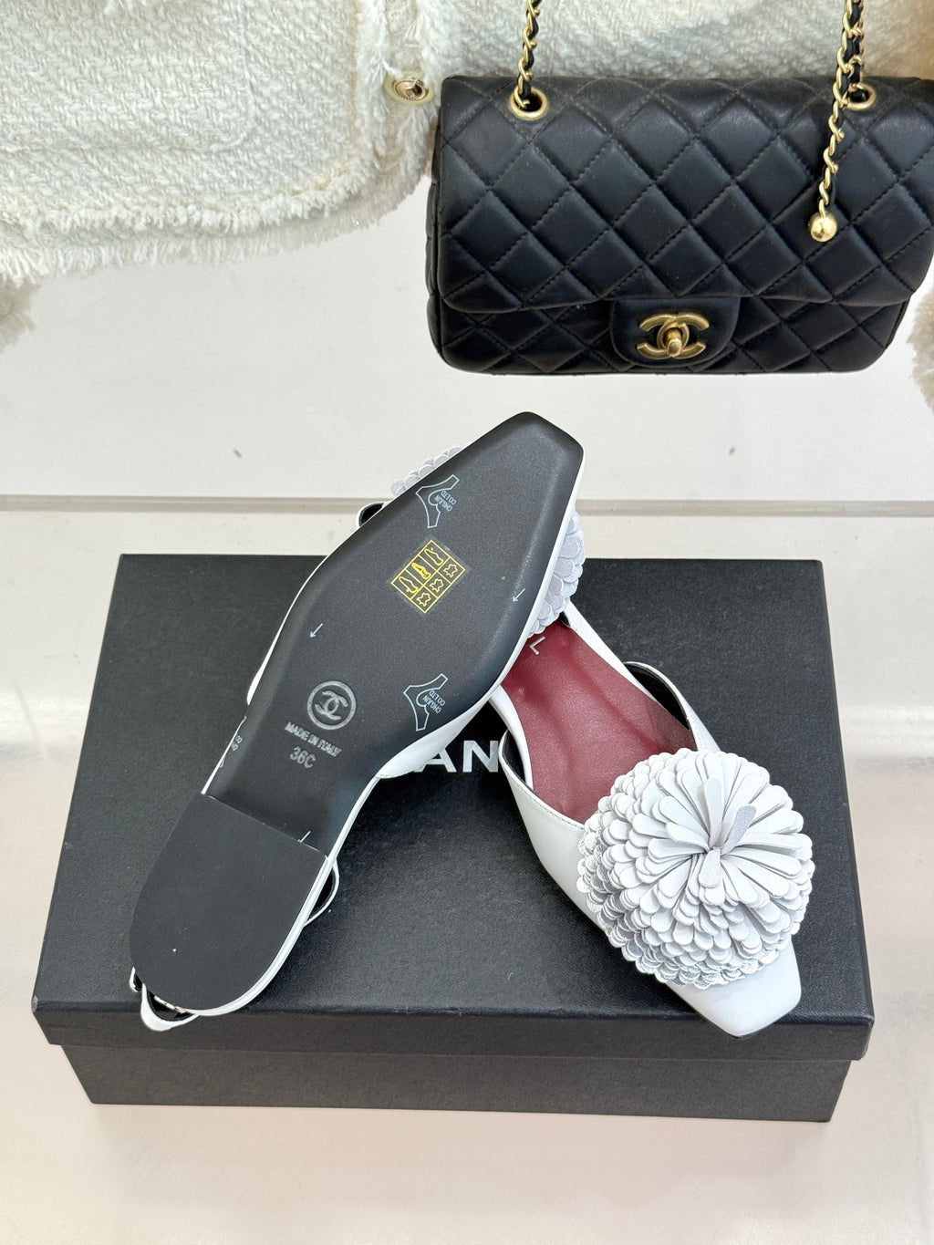 Chanel slingback flats with white flower appliqués and maroon interior on a box