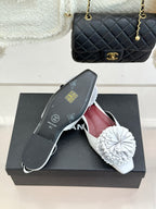 Chanel slingback flats with white flower appliqués and maroon interior on a box