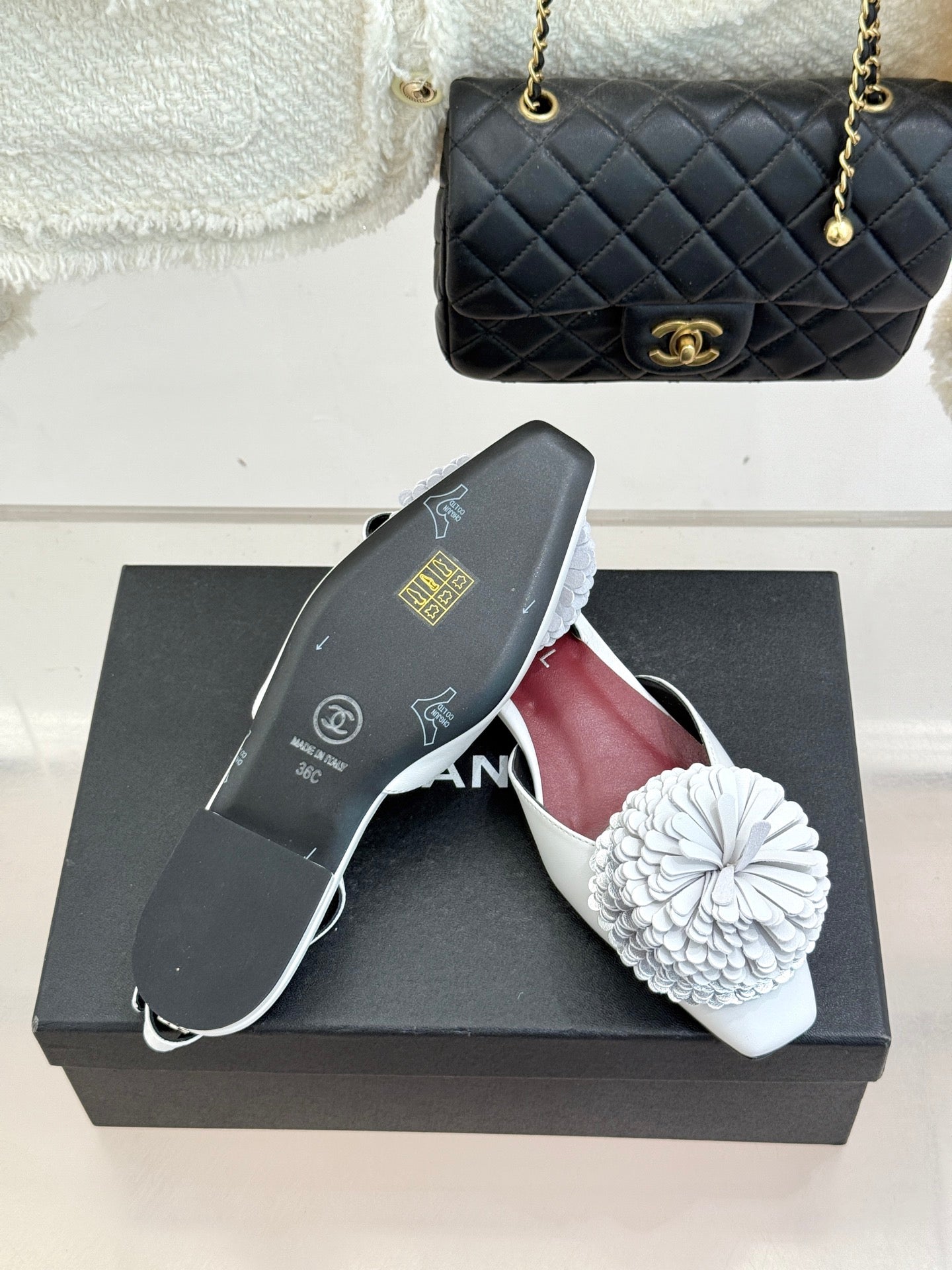 Chanel slingback flats with white flower appliqués and maroon interior on a box