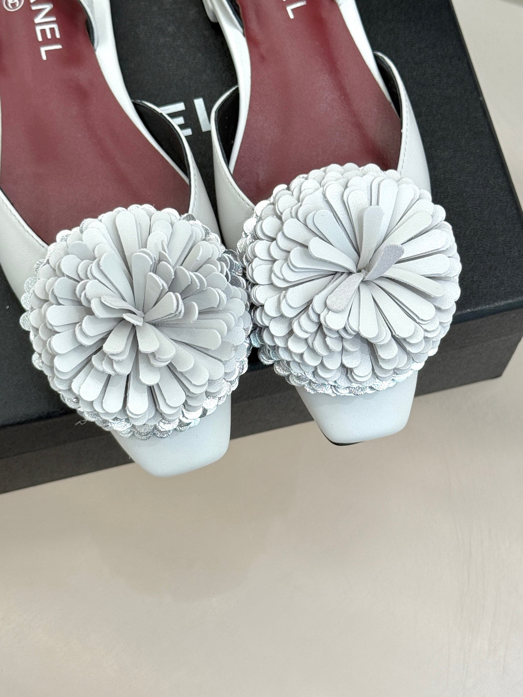 Chanel slingback flats with large white flower appliqués, front view