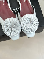 Chanel slingback flats with large white flower appliqués, front view