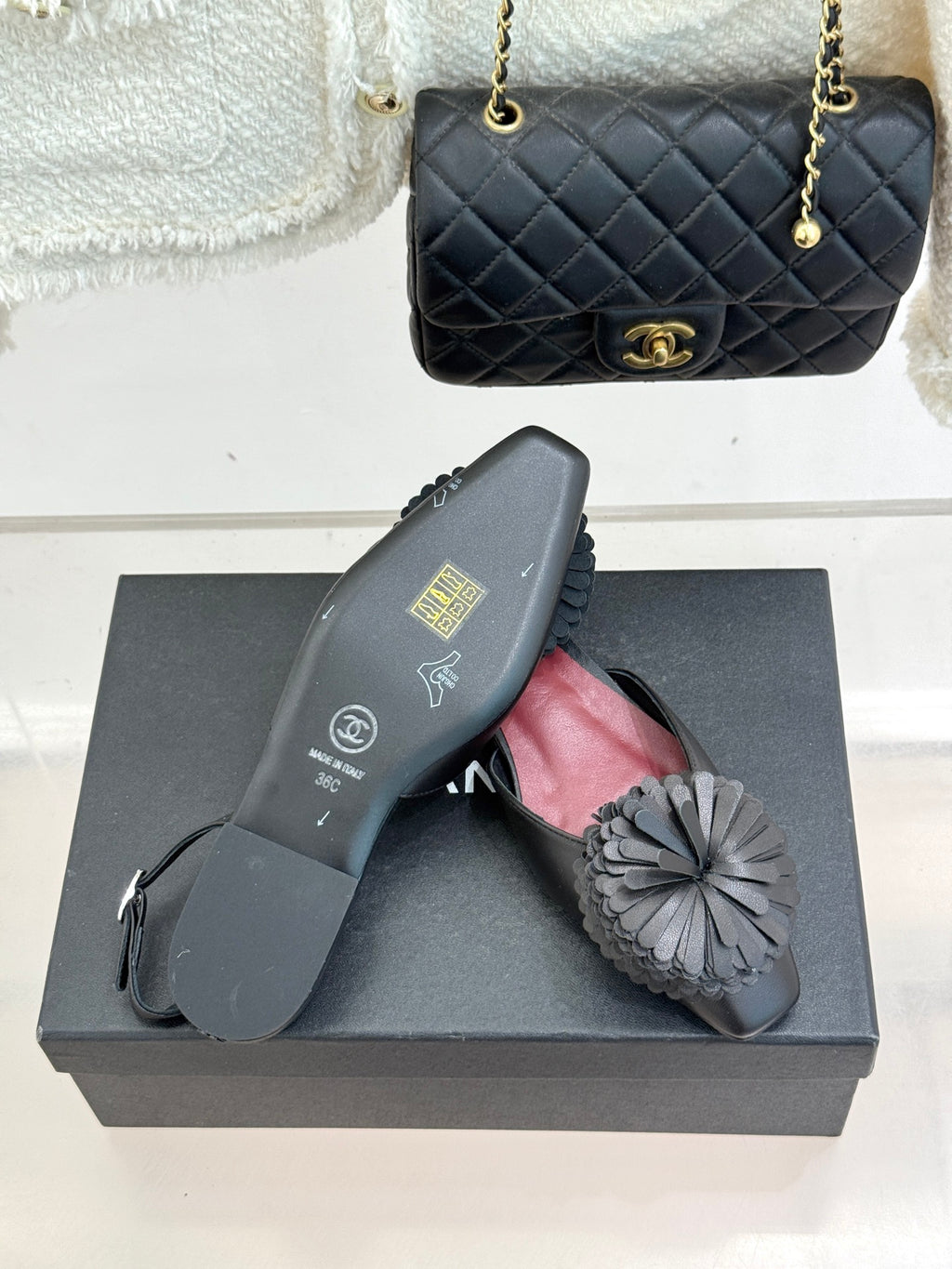 Black slingback flats with gray flower appliqué and red insole on dark shoe box