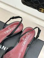 Black Chanel slingback flats with pink insoles and straps, shown on shoe box