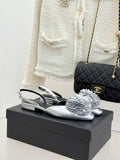 Silver Chanel slingback sandals with black straps and white flower embellishment