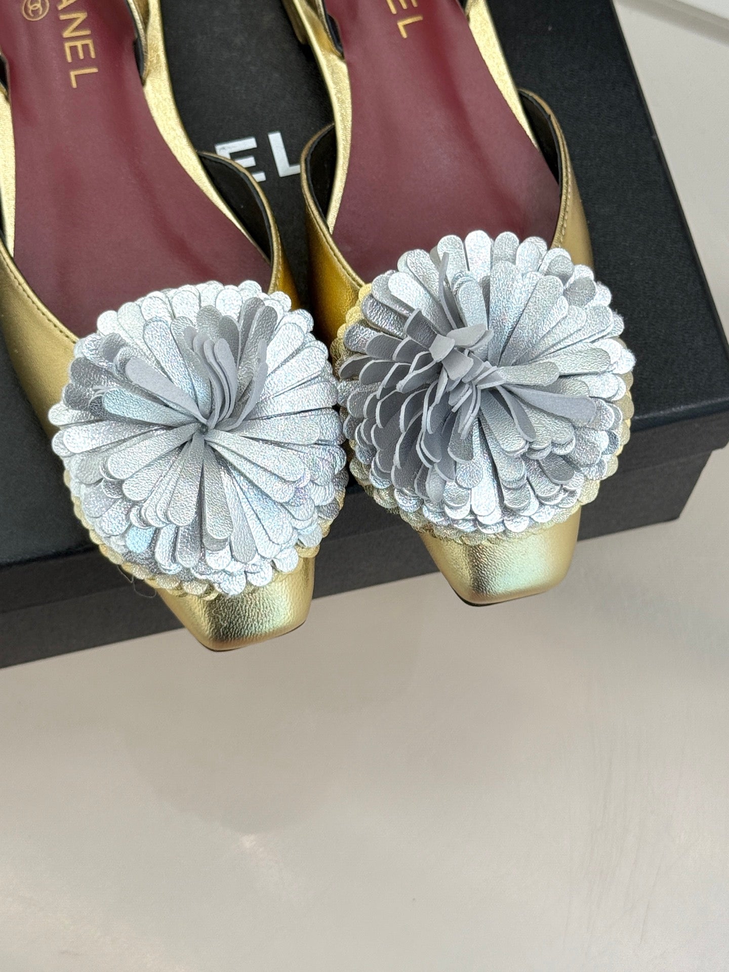 Gold slingback shoes with oversized white flower appliques and pointed toe