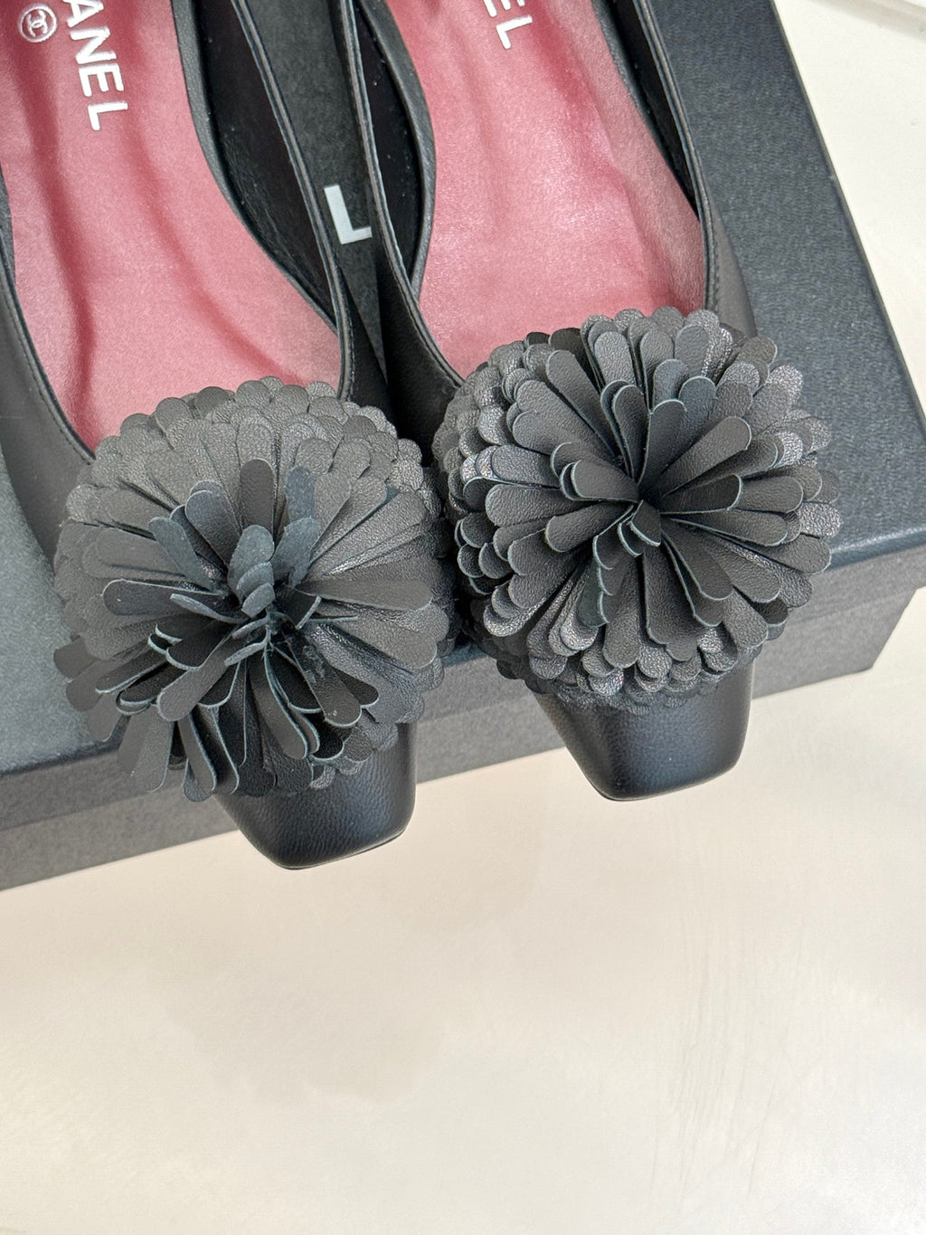 Chanel dark flats close-up with large gray flower appliques on toe