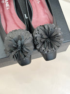 Chanel dark flats close-up with large gray flower appliques on toe