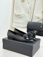 Chanel black leather flats with quilted texture and gray flower appliques