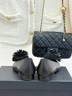 Chanel dark flats with gray pom-pom flower details, heel view