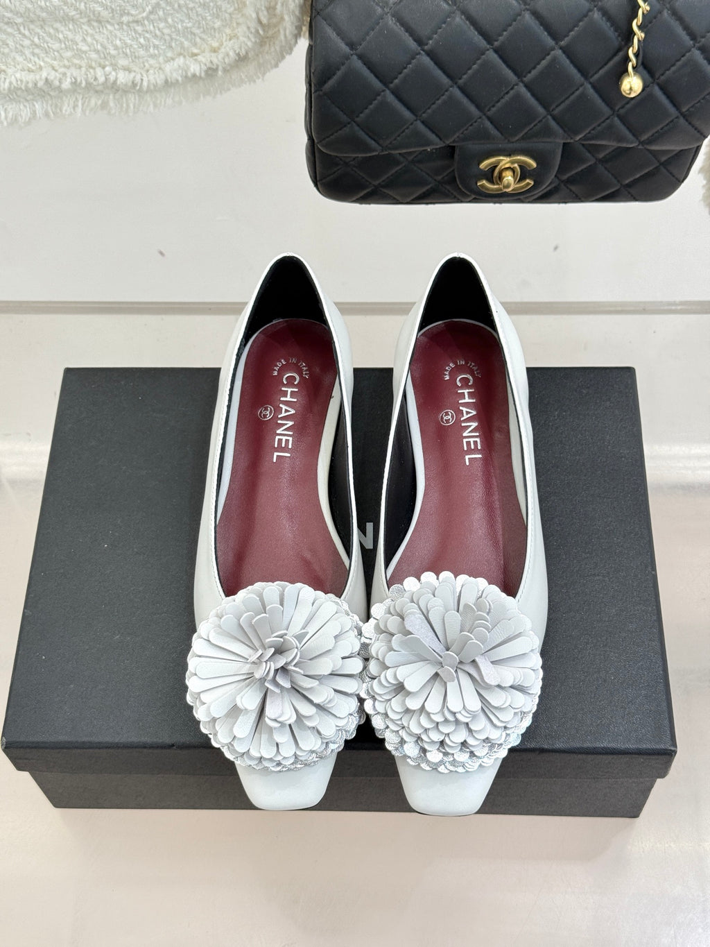 White women's flats with 3D flower appliques and rear profile on display