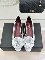 White women's flats with 3D flower appliques and rear profile on display