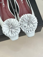 Close-up of white flats with large 3D flower appliques on the toes