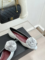 White slip-on flats with 3D flower appliques on a low, flat sole