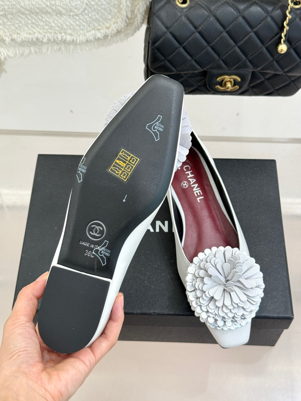 White flats with 3D flower appliques and Chanel branding on inner lining