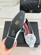 White flats with 3D flower appliques and Chanel branding on inner lining