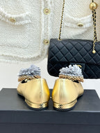 Back view of gold Chanel flats with white fabric flower details and gold heels