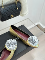 Gold Chanel flats with white fabric flowers and CHANEL on burgundy insoles