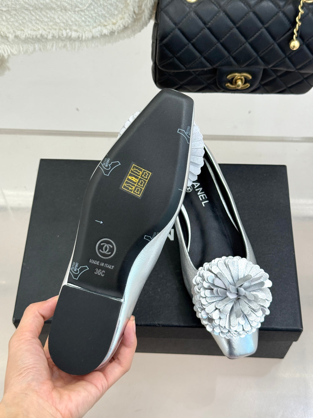 Chanel ladies silver ballet flats in hand, with white flower toe detail