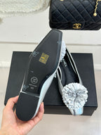 Chanel ladies silver ballet flats in hand, with white flower toe detail