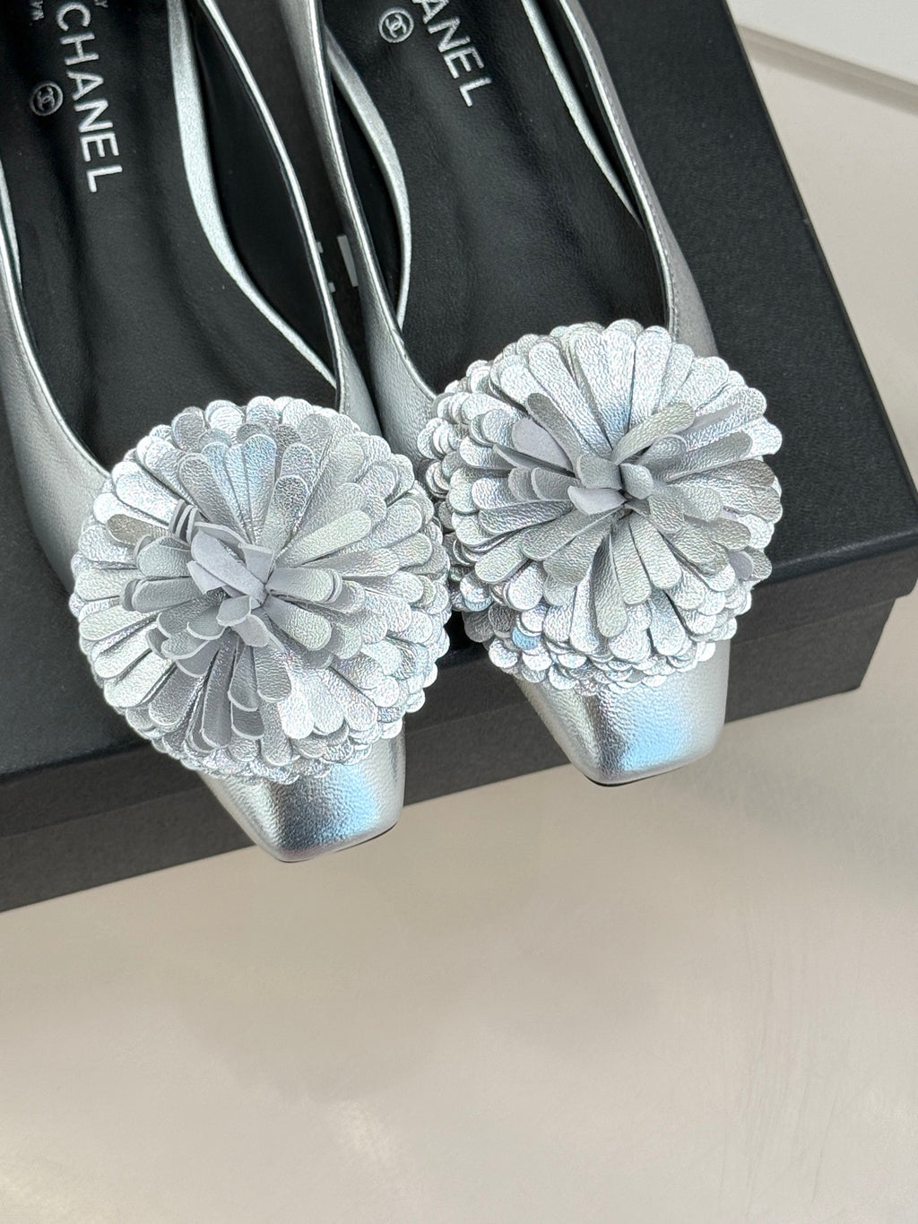 Close-up of Chanel ladies silver flats with large white flower appliques