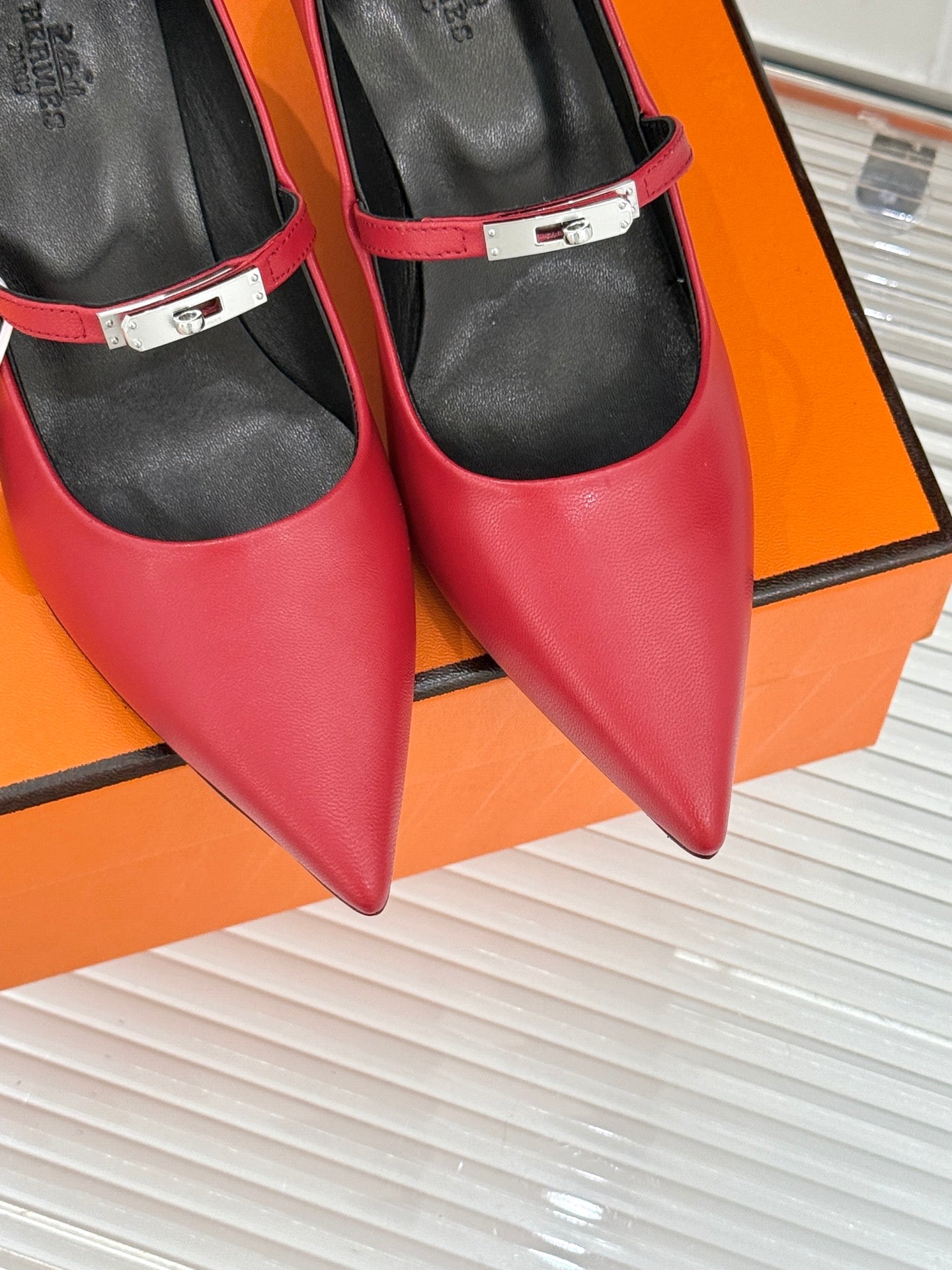 Close-up of red pointed-toe pumps with slingback strap and metal buckle.
