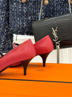 Red leather pump with slim heel, black lining, and slingback strap; metal buckle.