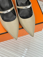 Close-up of cream pumps with black inner lining and metal buckle strap