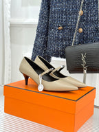 Pointed-toe leather pumps in cream with black interior and slingback strap