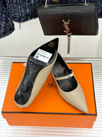 Cream pointed pumps with black lining on orange box, with slingback strap