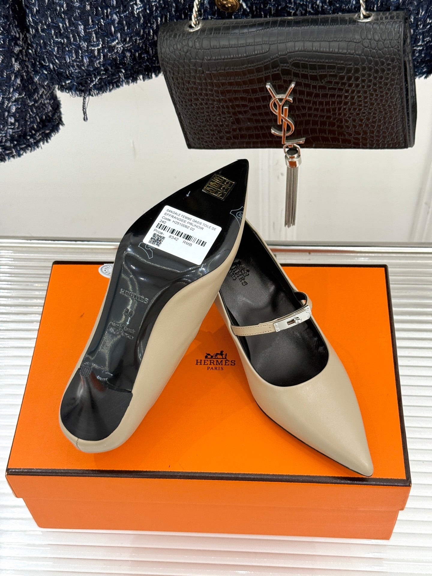 Cream pointed pumps with black lining on orange box, with slingback strap