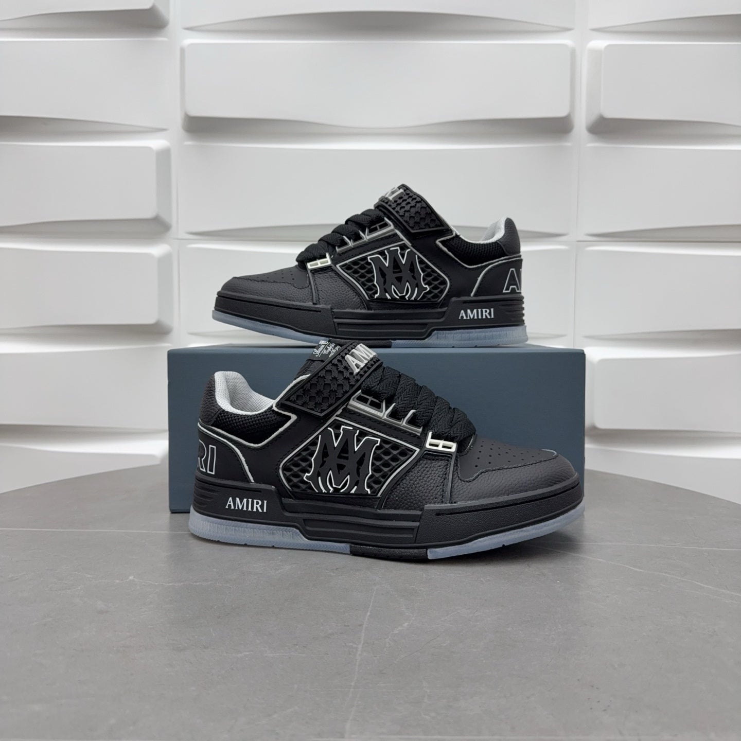 Pair of black low-top sneakers on blue boxes with lace strap and side emblem