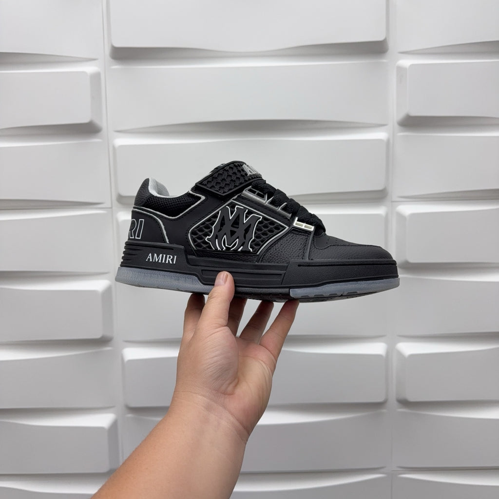 Luxury low-top sneaker in black with strap, textured upper, and AMIRI side logo
