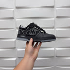Luxury low-top sneaker in black with strap, textured upper, and AMIRI side logo