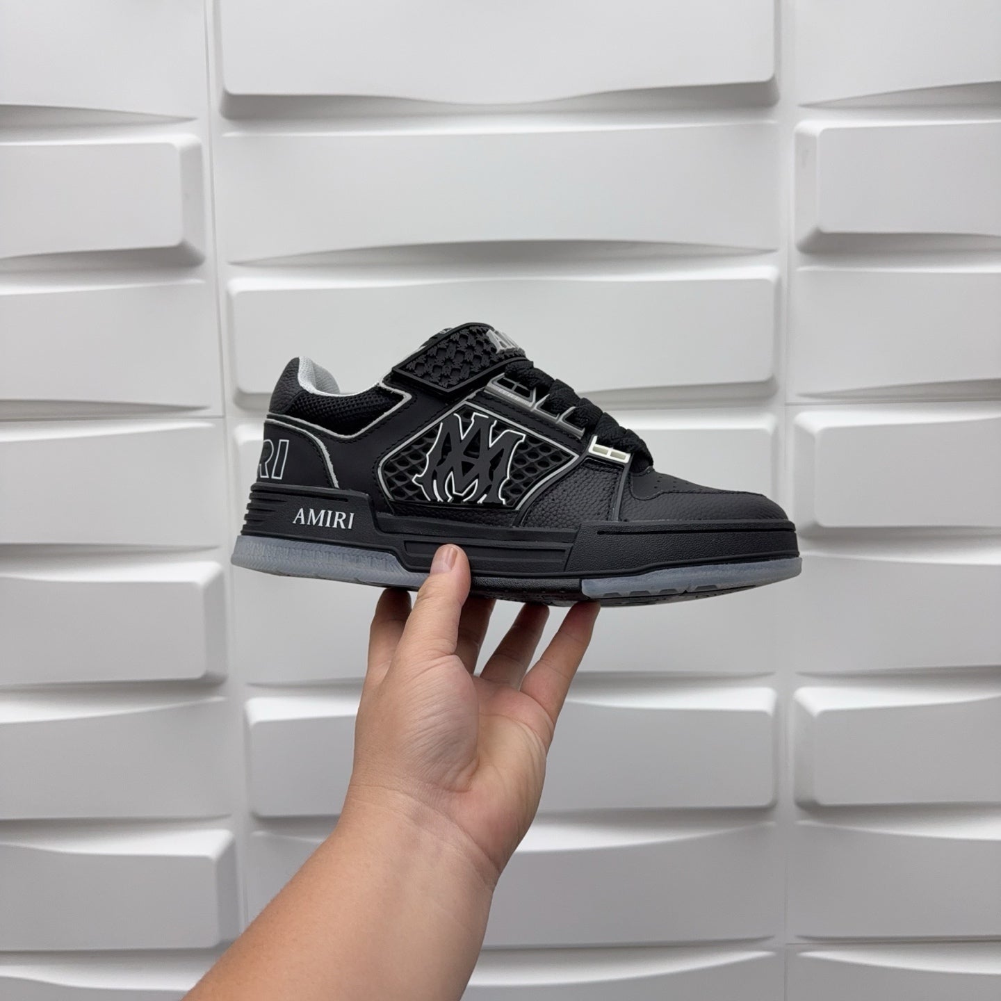 Luxury low-top sneaker in black with strap, textured upper, and AMIRI side logo