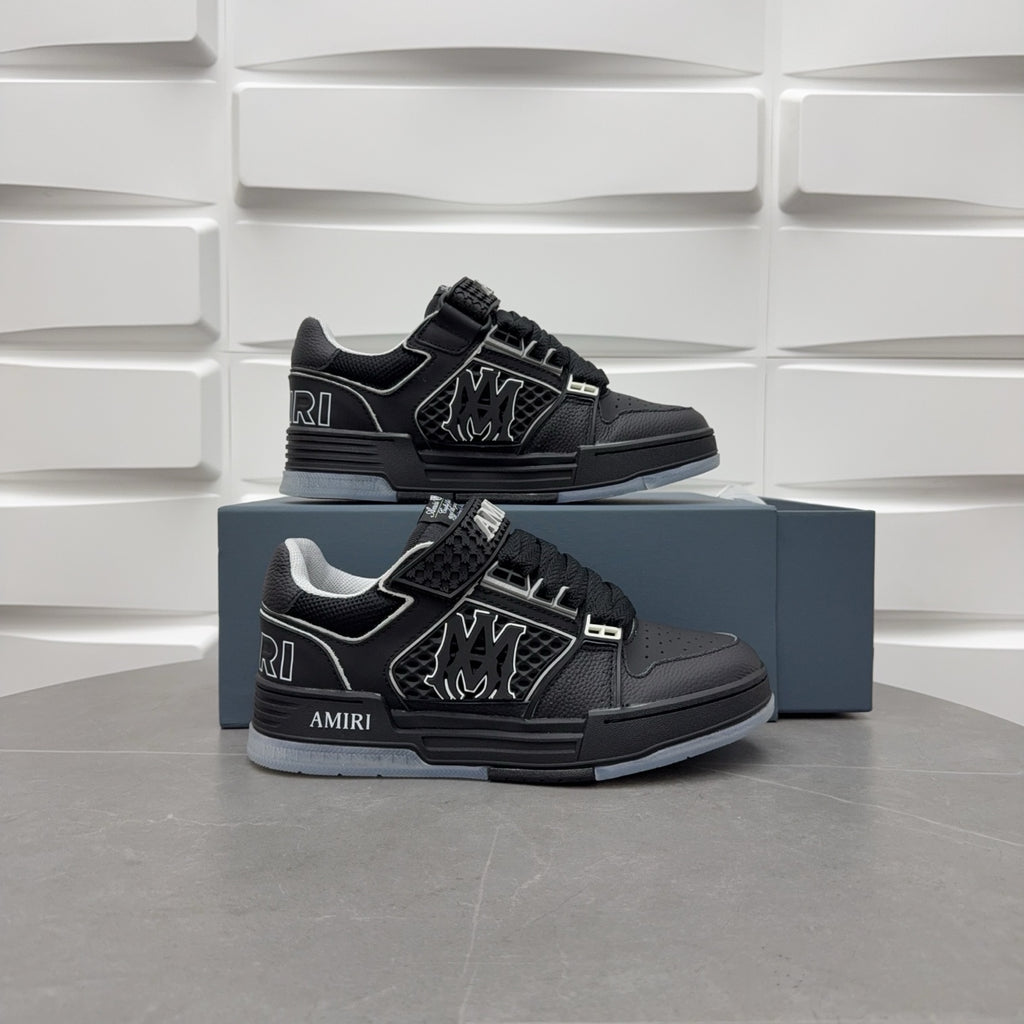 Pair of black low-top luxury sneakers with lace strap and side emblem on blue box