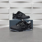 Pair of black low-top sneakers with strap details and side emblem on blue boxes
