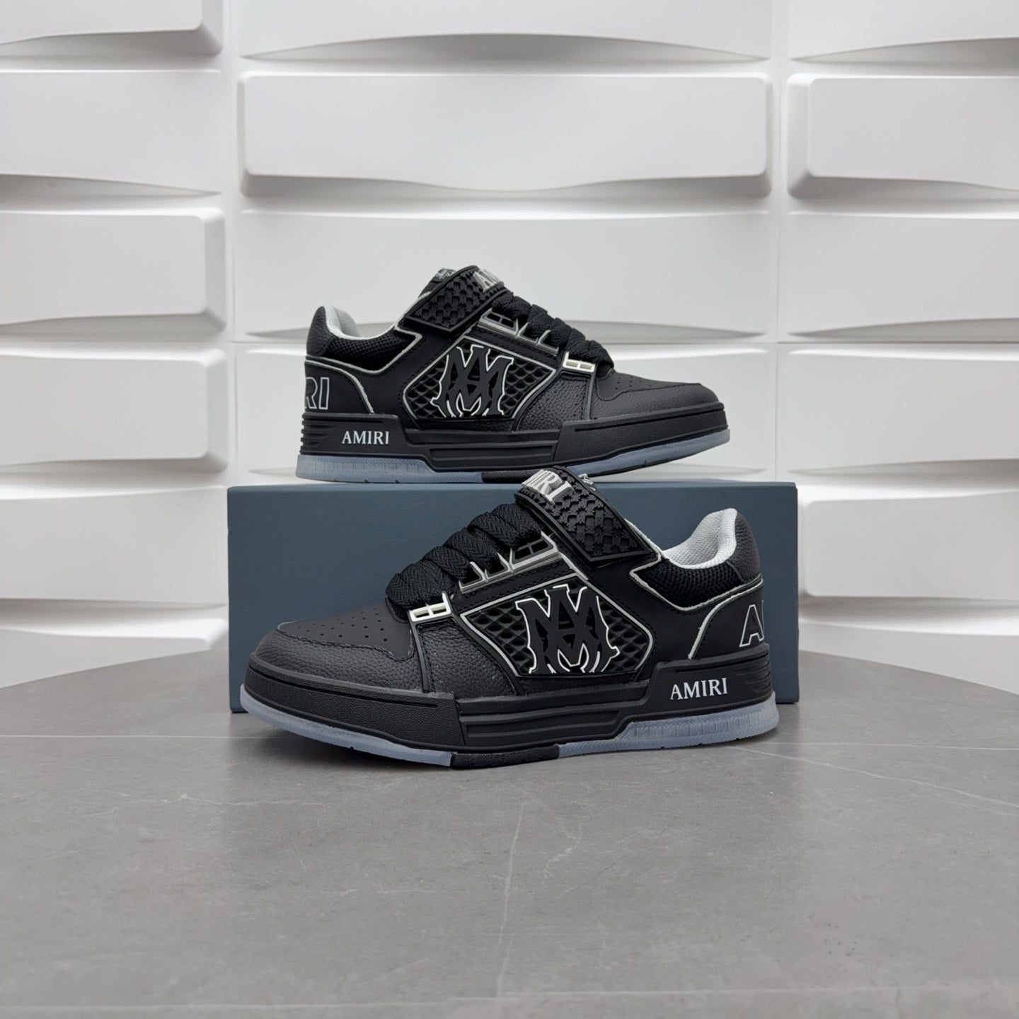 Pair of black low-top sneakers with strap details and side emblem on blue boxes