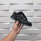 Luxury low-top sneaker in black with embossed side emblem and lace-up strap detail
