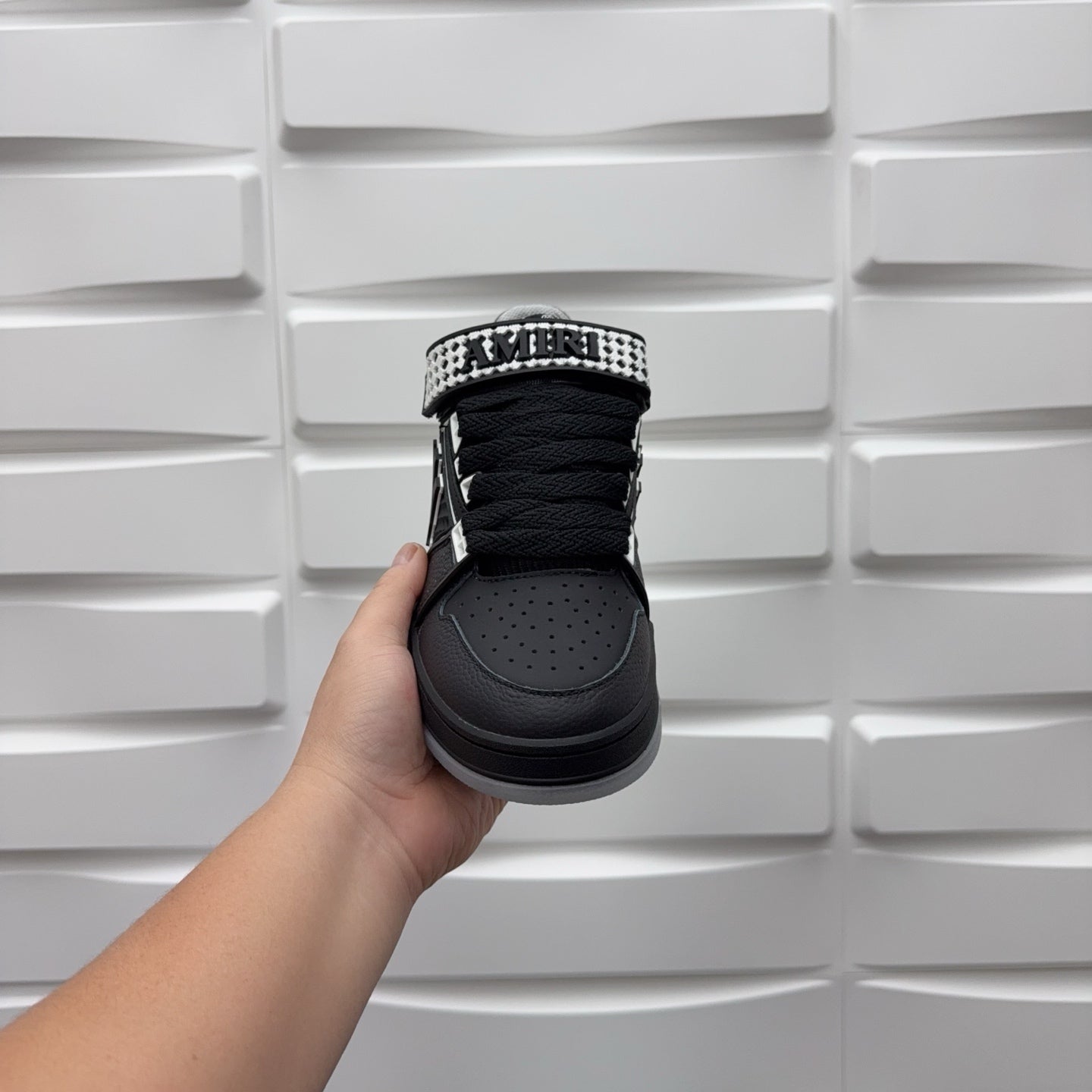 Black low-top sneaker heel with checkerboard collar strap, lace-up top view.