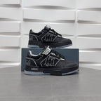 Pair of black low-top sneakers with checkerboard strap and graphic logo, on box.