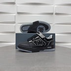 Black low-top sneaker outsole view with checkerboard strap and graphic logo.