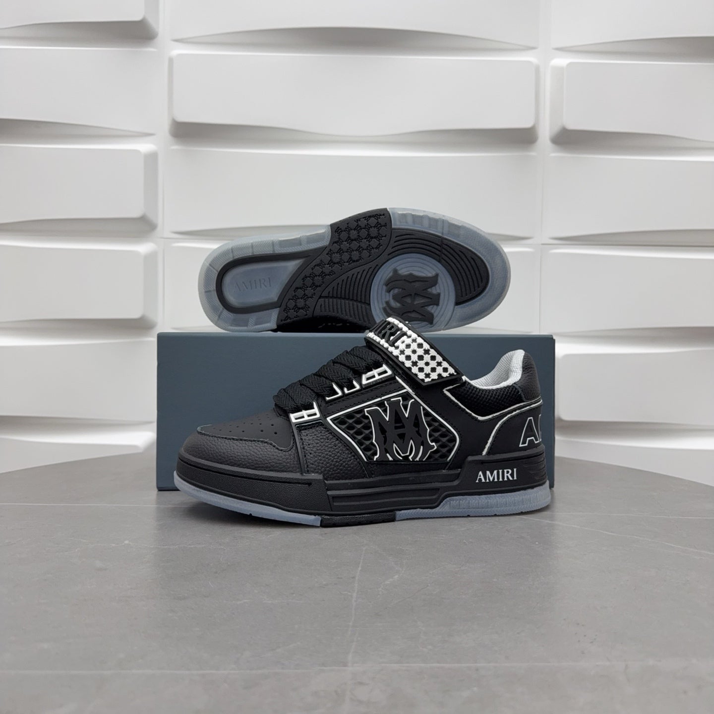 Black low-top sneaker outsole view with checkerboard strap and graphic logo.