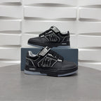 Black low-top sneakers with checkerboard strap and graphic logo, shown with box.
