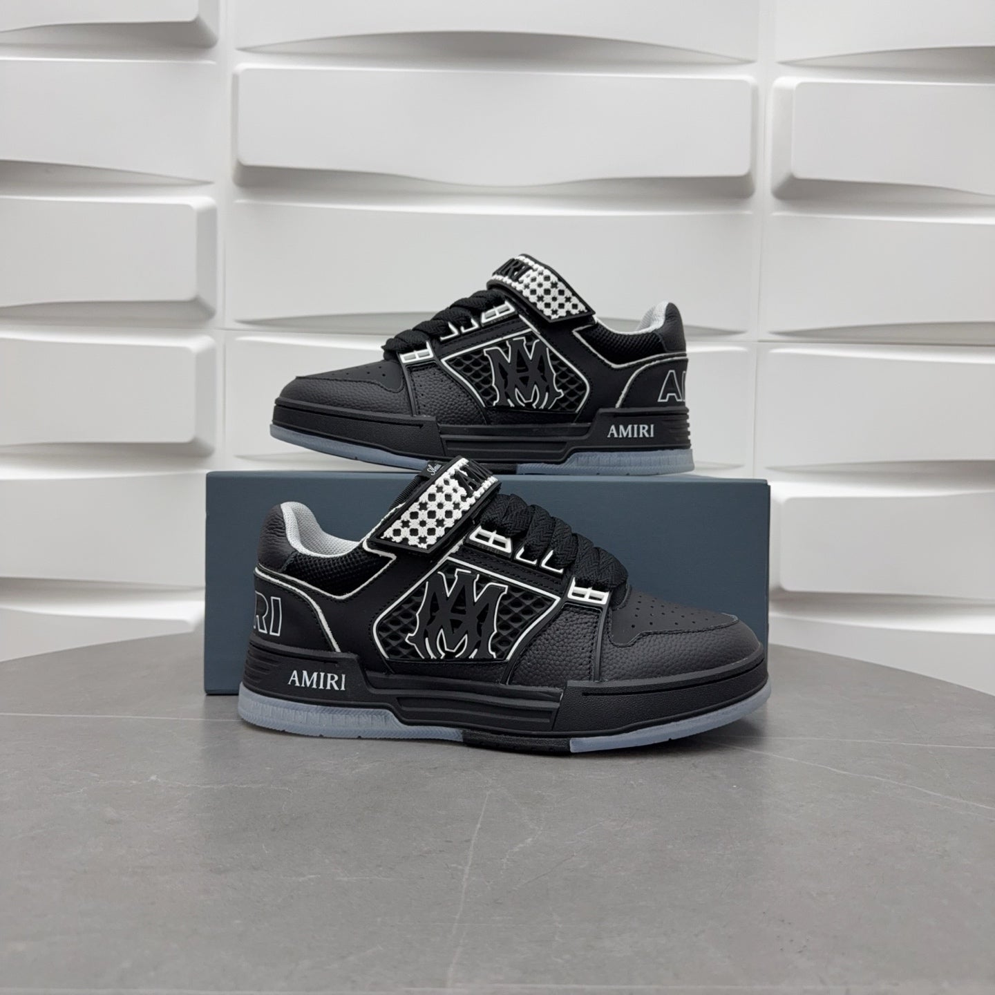 Black low-top sneakers with checkerboard strap and graphic logo, shown with box.