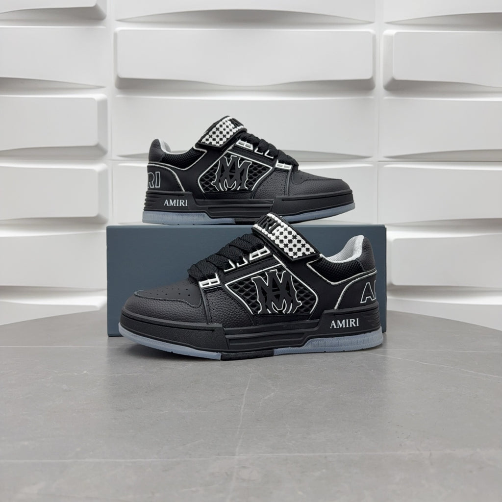 Two black low-top sneakers on box with checkerboard strap and graphic logo.