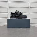 Black low-top sneakers with checkerboard strap and bold graphic logo, on box.